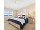 A well-lit bedroom with ocean views, featuring a queen size bed, matching nightstand, and a ceiling fan at 8030 Manasota Key Rd, Englewood, FL 34223