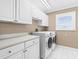 Well-lit laundry room with white cabinets, a countertop, and modern appliances at 8030 Manasota Key Rd, Englewood, FL 34223