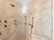 A large walk-in shower tiled with natural stone, a built-in seat and multiple shower heads and controls at 8030 Manasota Key Rd, Englewood, FL 34223