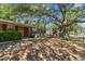 Charming single-story home with a red front door, mature trees and a partially shaded front yard at 9402 N Newport Ave, Tampa, FL 33612