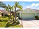 Home exterior with attached two car garage, well-maintained lawn and garden featuring decorative plants at 11466 Captiva Kay Dr, Riverview, FL 33569