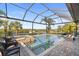 A luxurious screened-in pool with a scenic waterfront view, complete with a cozy fire pit and comfortable seating at 11506 Harbourside Ln, Parrish, FL 34219