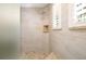 Walk-in shower featuring stone floors and tiles, a built-in shelf, and shuttered windows at 11506 Harbourside Ln, Parrish, FL 34219