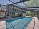 A lovely in-ground swimming pool surrounded by brick, covered by a screen enclosure, with a two-story home as a backdrop at 13004 Bell Creek Chase, Riverview, FL 33569
