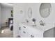 Bright modern bathroom features double sinks, quartz countertops, and a round mirror at 13117 4Th E St, Madeira Beach, FL 33708