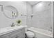 Modern bathroom features a gray vanity, round mirror, and a shower and tub combo at 13117 4Th E St, Madeira Beach, FL 33708