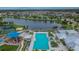 Aerial view of community pool, with blue umbrellas and lounge chairs, a playground, and serene lake at 15718 Fort Island Pl, Sun City Center, FL 33573