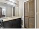 Bathroom with a black vanity, large mirror, and wooden closet door in need of repair at 16169 Gardendale Dr, Tampa, FL 33624