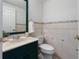 Powder room featuring a tile backsplash, neutral walls, decorative wallpaper and a dark green vanity cabinet at 1695 Pinellas Bayway S # E6, St Petersburg, FL 33715