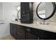 Double vanity bathroom featuring dark cabinets, stone backsplash, and round mirrors at 1695 Pinellas Bayway S # E6, St Petersburg, FL 33715
