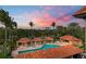 Overhead shot of the pool with covered cabanas and well manicured landscaping with palm trees at sunset at 1695 Pinellas Bayway S # E6, St Petersburg, FL 33715