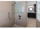 Tiled shower with glass blocks and view of the bathroom vanity and round mirror at 1695 Pinellas Bayway S # E6, St Petersburg, FL 33715