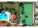 Overhead view of tennis court and pool, surrounded by lush landscaping and quaint cabana, perfect for outdoor activities at 1695 Pinellas Bayway S # E6, St Petersburg, FL 33715