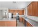Well-lit kitchen boasts wood cabinets, stainless steel appliances, an island, and wood-look flooring at 18837 Litzau Ln, Land O Lakes, FL 34638