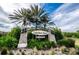 View of the Lake Shore Ranch entrance sign flanked by palm trees and lush landscaping under a partly cloudy sky at 19610 Sunset Bay Dr, Land O Lakes, FL 34638