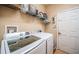 Laundry room featuring appliances, storage shelf, and tile floors at 19610 Sunset Bay Dr, Land O Lakes, FL 34638
