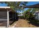 View of the backyard with an enclosed patio, lush greenery, and a tree providing shade at 3039 Sean Way, Palm Harbor, FL 34684