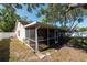 Exterior view of the home featuring a screened-in patio and a spacious backyard at 3039 Sean Way, Palm Harbor, FL 34684