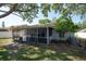 Backyard view featuring a screened-in patio, trees, and a spacious lawn at 3039 Sean Way, Palm Harbor, FL 34684