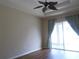 Bedroom featuring neutral paint, tray ceiling, wood flooring, ceiling fan, and slider glass door at 30434 Colehaven Ct, Wesley Chapel, FL 33543