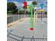 Community splash pad with colorful water features, playground, and a surrounding safety fence at 30434 Colehaven Ct, Wesley Chapel, FL 33543