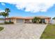 Charming one-story home boasting an expansive brick driveway, lush landscaping, and a classic terracotta roof, enhancing curb appeal at 3235 Seaway Dr, New Port Richey, FL 34652