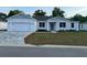 Charming single-story home featuring a well-manicured lawn and a brick-paved driveway and a modern, white facade at 37565 Teri Ct, Dade City, FL 33525