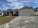 Charming one-story home featuring a stylish gray exterior, a paver driveway, and well-manicured landscaping at 37565 Teri Ct, Dade City, FL 33525