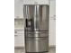 Stainless steel refrigerator in a well-lit kitchen featuring white cabinetry and decorative backsplash at 37565 Teri Ct, Dade City, FL 33525