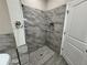 Modern shower features elegant marble tile, pebble flooring, and built-in niche at 37565 Teri Ct, Dade City, FL 33525