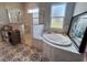 Bright primary bathroom featuring a soaking tub, glass enclosed shower and decorative tile floor at 4294 Cork Rd, Plant City, FL 33565