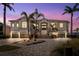 Grand two-story house with a lush tropical landscape, circular driveway, and inviting front entrance at dusk at 6202 Pasadena Point Blvd, Gulfport, FL 33707