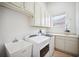Well-lit laundry room with white cabinets and modern appliances at 6202 Pasadena Point Blvd, Gulfport, FL 33707