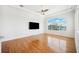 Bright living room with hardwood floors, a large arched window with water views, and a mounted television at 6202 Pasadena Point Blvd, Gulfport, FL 33707