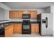 Kitchen with wooden cabinets, black appliances, and light wood flooring, complete with stainless steel fridge at 6831 Dartmouth Hill St, Riverview, FL 33578