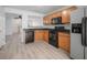 Kitchen with wooden cabinets, black appliances, and light wood flooring, with connecting view to living room at 6831 Dartmouth Hill St, Riverview, FL 33578