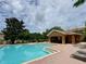 Community pool featuring brick patio, palm trees, lounge chairs, cabana, and a serene view of the blue sky at 6831 Dartmouth Hill St, Riverview, FL 33578