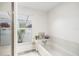 Bright bathroom showcasing a tub with tile surround, shower, and a window with a view of outdoor foliage at 736 85Th N Ave, St Petersburg, FL 33702