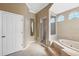 Bright bathroom featuring a glass shower, garden tub, arched windows, and neutral colors at 9127 Irondale Ln, Hudson, FL 34667