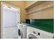 Laundry room with washer, dryer, storage, and entry to carpeted room at 9127 Irondale Ln, Hudson, FL 34667