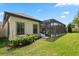 An exterior view of home with a screened-in pool and patio area, surrounded by lush green grass and landscaped bushes at 922 Grand Cresta Ave, Brandon, FL 33511