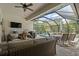 An indoor outdoor living space with rattan furniture, a TV, ceiling fan, and access to the screened in swimming pool at 922 Grand Cresta Ave, Brandon, FL 33511