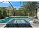 A luxurious screened in swimming pool with blue mosaic tile work and a hot tub, perfect for relaxation and recreation at 922 Grand Cresta Ave, Brandon, FL 33511