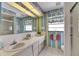 Colorful bathroom with double sinks, striped wallpaper, and a window with playful curtains at 927 Golf Island Dr, Apollo Beach, FL 33572