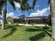 Lush backyard featuring manicured lawn, tropical palms, a screened lanai, and clean white rock landscaping at 1137 Treasure Cay Ct, Punta Gorda, FL 33950