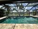 A screened pool with stone surround reflects palm trees in a waterfront backyard at 1137 Treasure Cay Ct, Punta Gorda, FL 33950