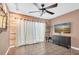 Bright living room with tile flooring, a ceiling fan, modern TV, wood accent wall and sheer curtains at 1180 39Th N St, St Petersburg, FL 33713