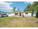 Inviting single-story home with a red door, complemented by a lush green front lawn at 12701 Cornell Ct, Hudson, FL 34667