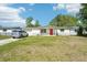 A cozy, single-story home with a bright red door, surrounded by a green lawn and a silver car parked in the driveway at 12701 Cornell Ct, Hudson, FL 34667