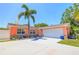 Charming coral home featuring a well-maintained front yard and a spacious two-car garage and a shade tree at 13024 124Th Ave, Largo, FL 33774